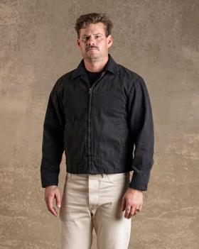 A man wearing a black Bradley Mountain waxed canvas work jacket with cream trousers