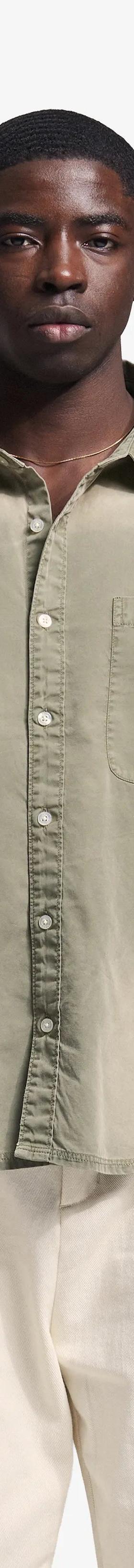 A man wearing a sage green Bram's Fruit overshirt with cream trousers