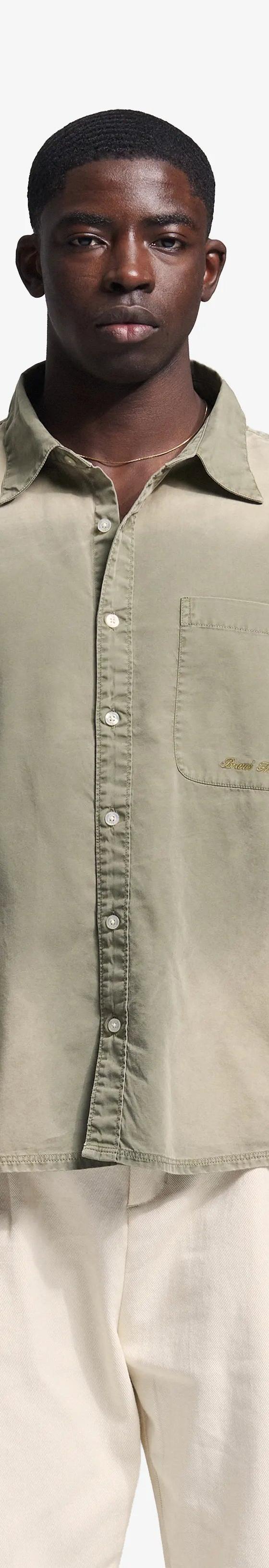 A man wearing a sage green Bram's Fruit overshirt with cream trousers