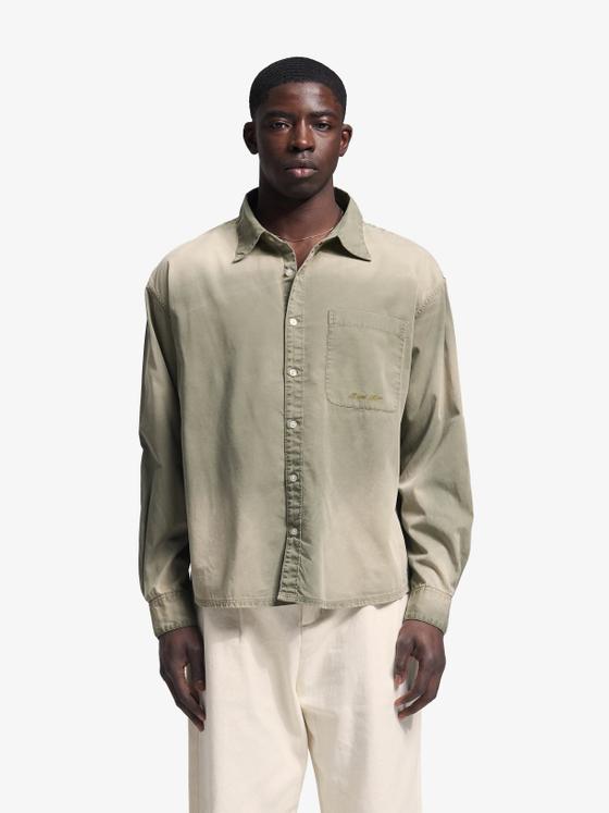 A man wearing a sage green Bram's Fruit overshirt with cream trousers