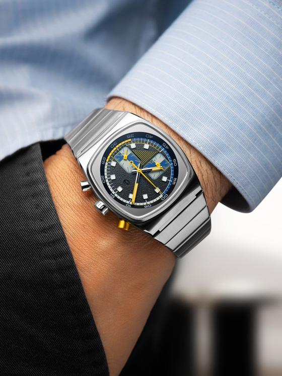 A man wearing a silver Brew Watch Co. chronograph with a black, blue and yellow dial