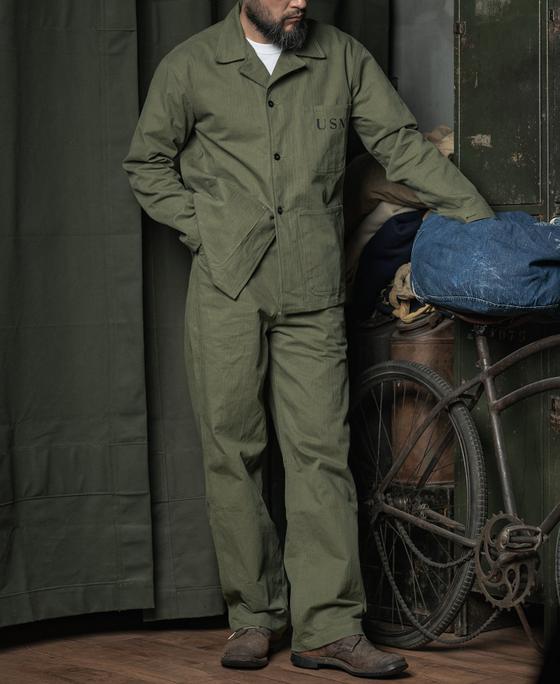 A man wearing a Bronson Mfg. Co. olive 1945 USN N-3 HBT utility jacket and trousers