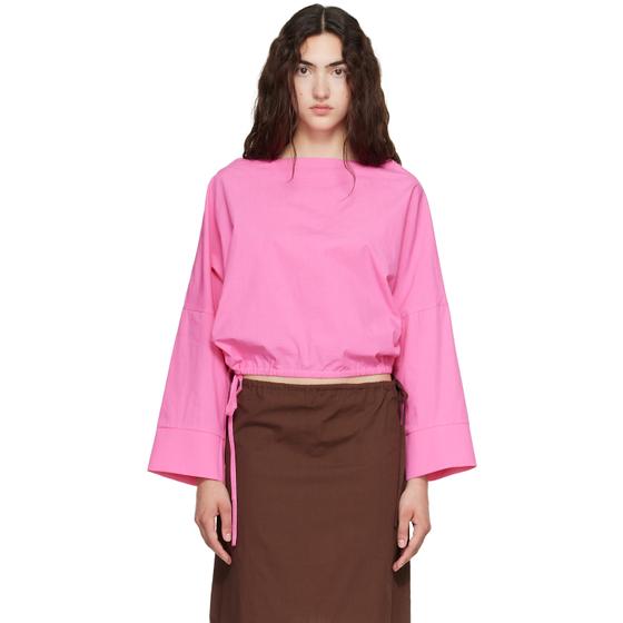 A woman wearing a pink Brooke Callahan cotton poplin top with a brown poplin skirt