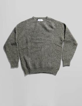 A grey brushed wool crewneck sweater laid flat on a soft white background