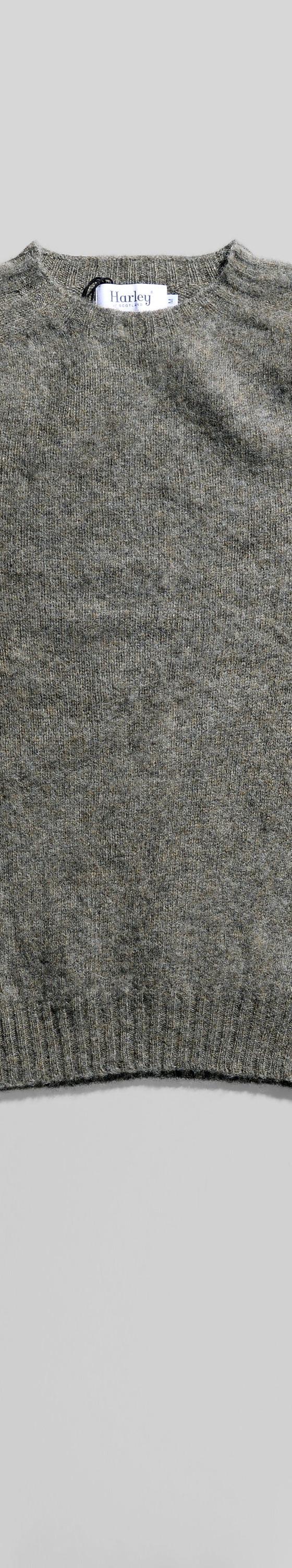 A grey brushed wool crewneck sweater laid flat on a soft white background
