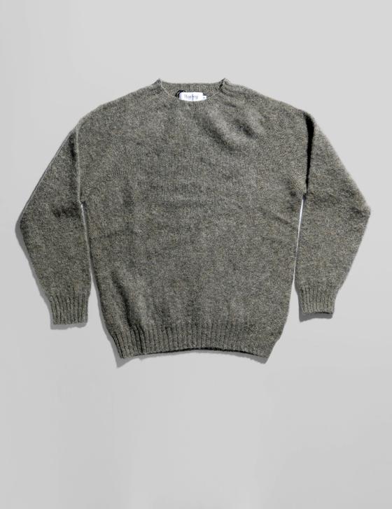 A grey brushed wool crewneck sweater laid flat on a soft white background