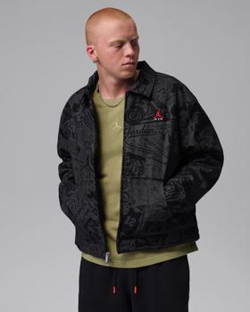 A man wearing a black all-over print Jordan coach jacket over an olive tee