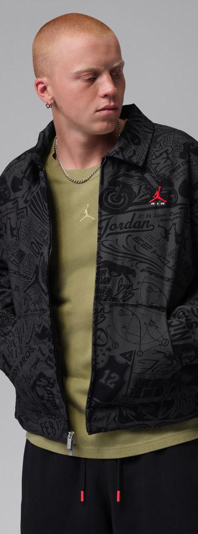 A man wearing a black all-over print Jordan coach jacket over an olive tee