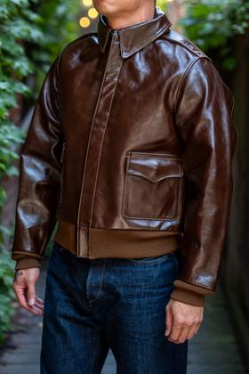 A man wearing a brown Buzz Rickson's A-2 leather flight jacket with dark indigo jeans