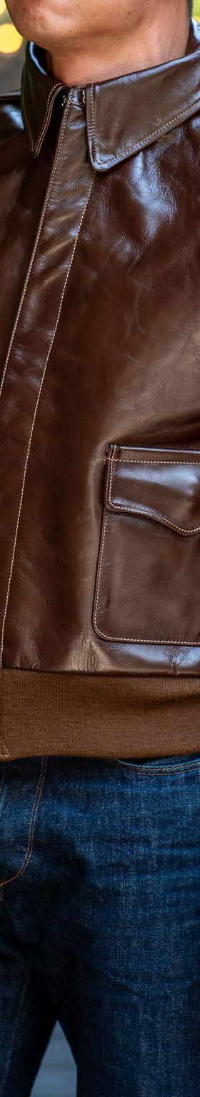 A man wearing a brown Buzz Rickson's A-2 leather flight jacket with dark indigo jeans