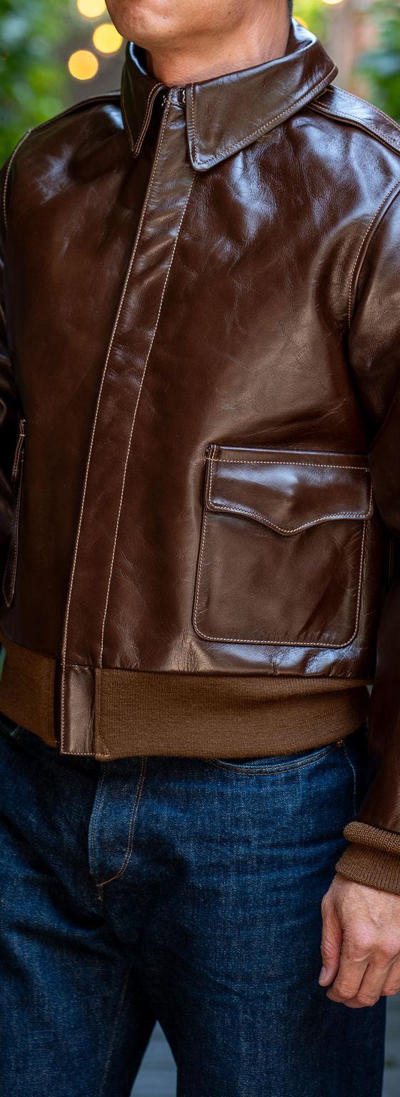 A man wearing a brown Buzz Rickson's A-2 leather flight jacket with dark indigo jeans