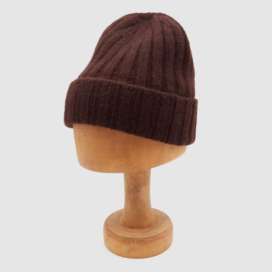 A dark brown ribbed wool Câbleami knit cap displayed on a wooden hat block