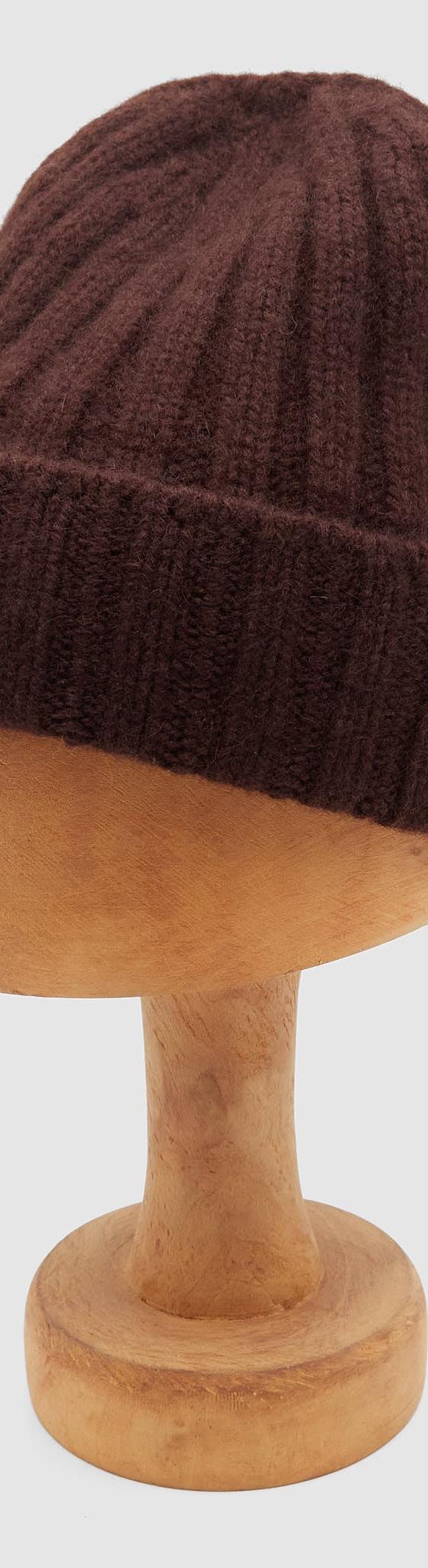 A dark brown ribbed wool Câbleami knit cap displayed on a wooden hat block