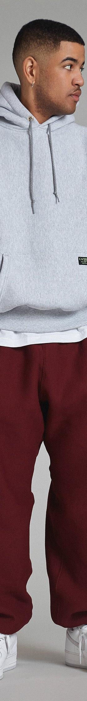 A man wearing a grey Camber USA heavyweight hooded sweatshirt with burgundy sweatpants