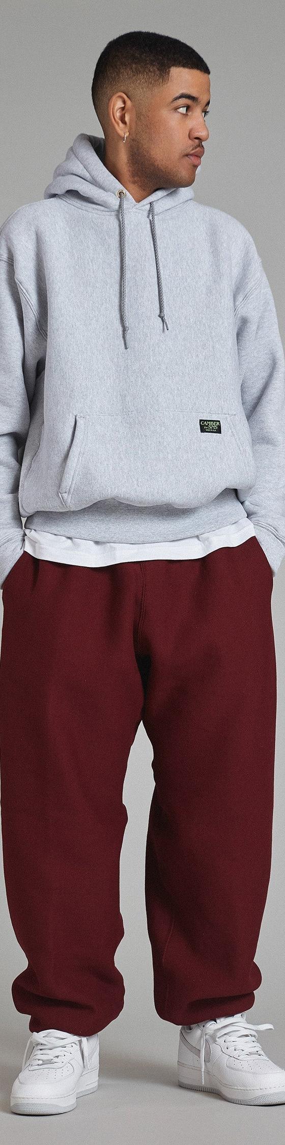 A man wearing a grey Camber USA heavyweight hooded sweatshirt with burgundy sweatpants