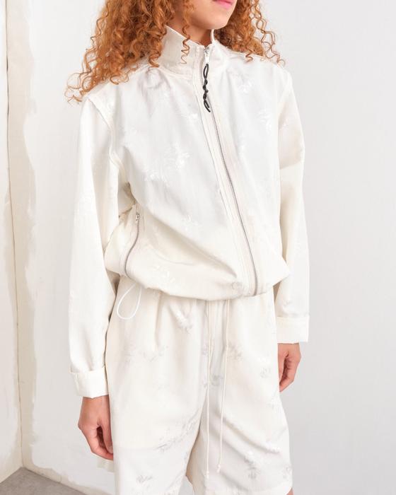 A woman wearing a cream Camiel Fortgens zip jacket and matching shorts