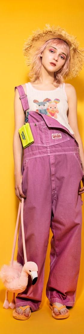 A woman wearing pink Candy Stripper overalls with a graphic tank top and straw hat