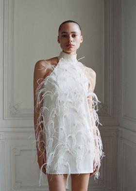 A woman wearing a white feather-embellished mini dress