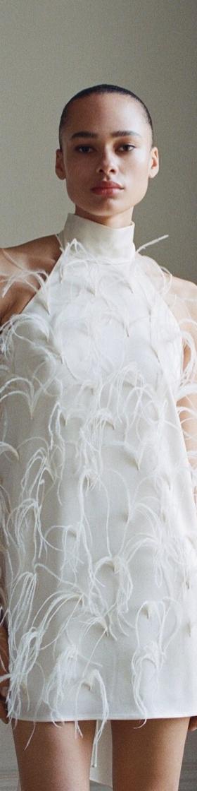 A woman wearing a white feather-embellished mini dress