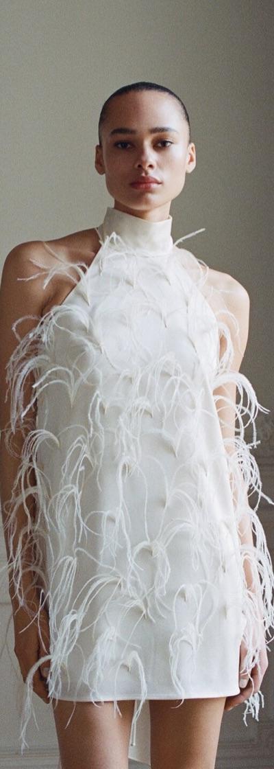 A woman wearing a white feather-embellished mini dress