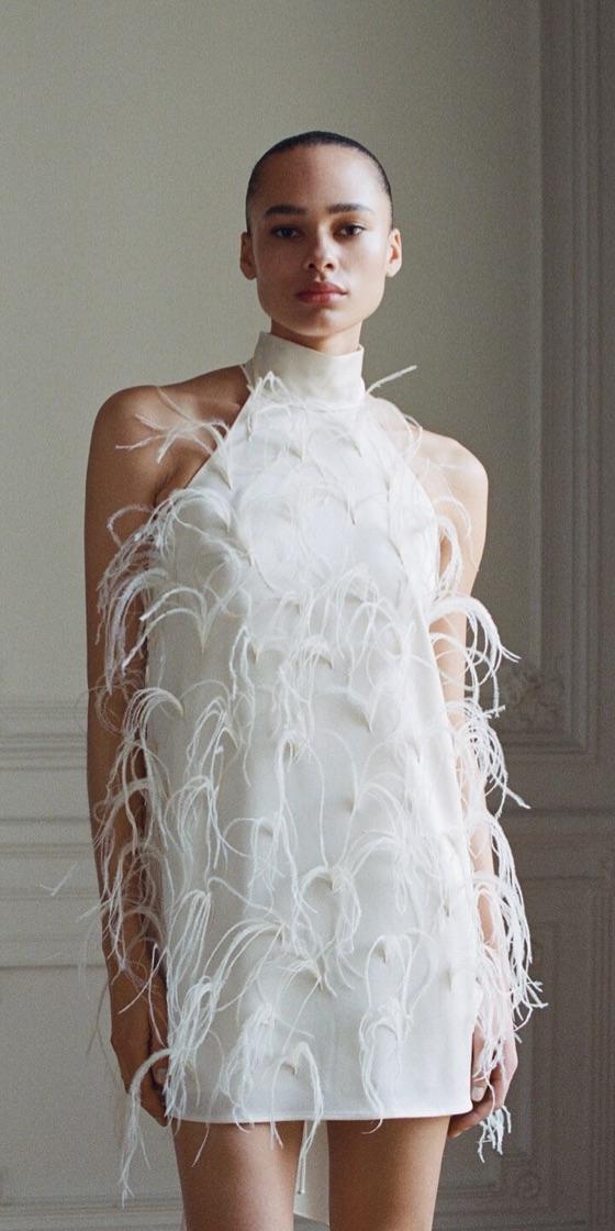 A woman wearing a white feather-embellished mini dress