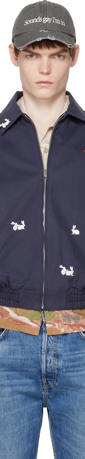 A man wearing a navy Carne Bollente embroidered bomber jacket and cap