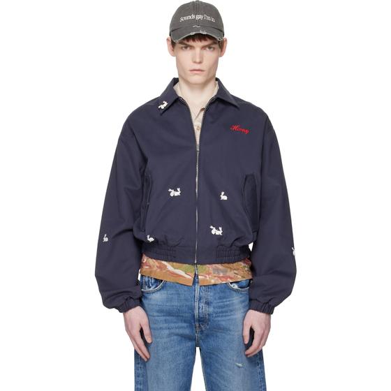 A man wearing a navy Carne Bollente embroidered bomber jacket and cap