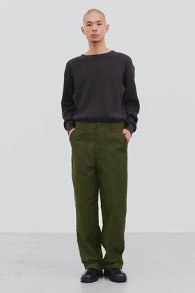 A man wearing a dark brown CIOTA crewneck sweater with olive wide-leg fatigue trousers