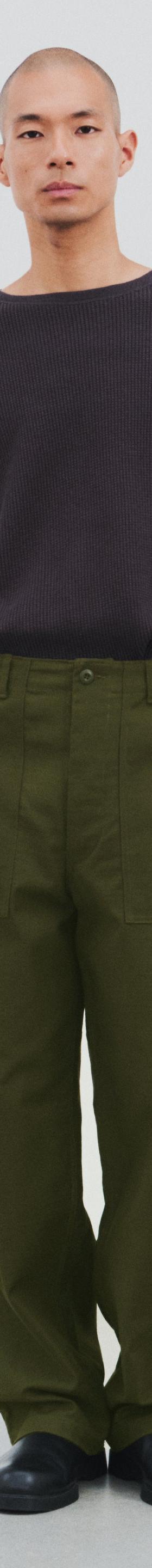 A man wearing a dark brown CIOTA crewneck sweater with olive wide-leg fatigue trousers