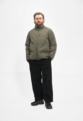 A man wearing an olive Cleptomanicx weatherproof jacket with black trousers