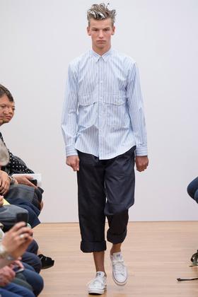 A man wearing a blue striped Comme des Garçons SHIRT poplin button-down with cropped navy trousers