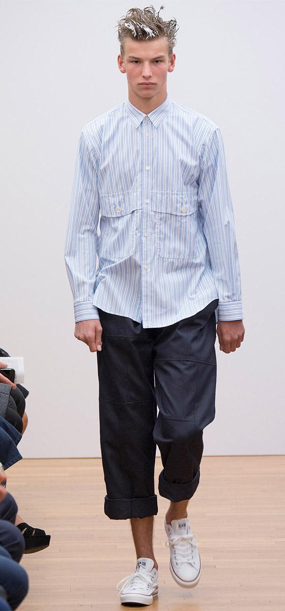 A man wearing a blue striped Comme des Garçons SHIRT poplin button-down with cropped navy trousers