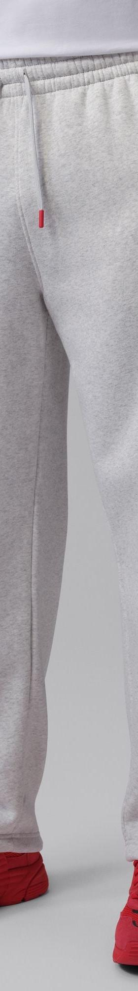 A man wearing grey Jordan fleece sweatpants with red sneakers