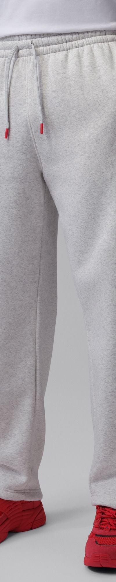A man wearing grey Jordan fleece sweatpants with red sneakers