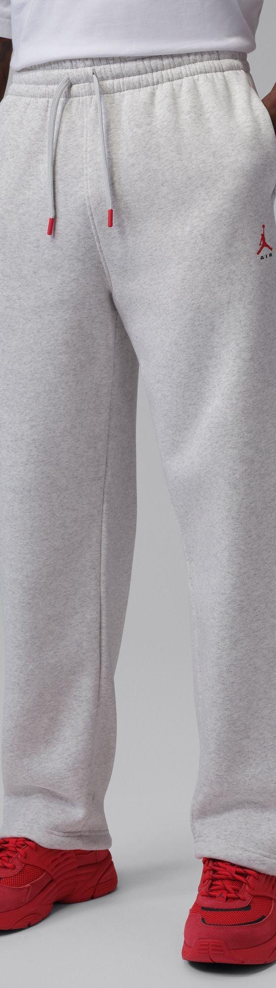 A man wearing grey Jordan fleece sweatpants with red sneakers
