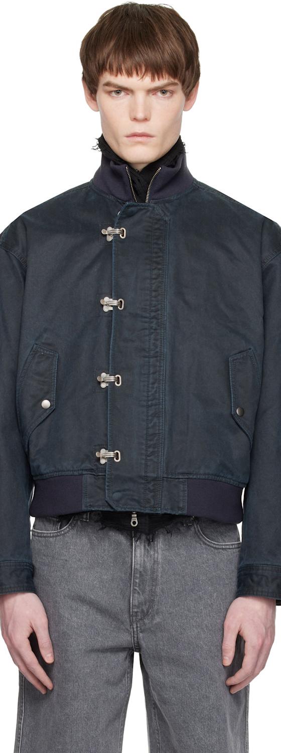 A man wearing a navy COOR blouson jacket with grey jeans
