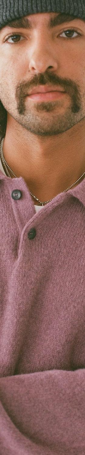 A man wearing a mauve Corridor brushed knit polo sweater and grey beanie