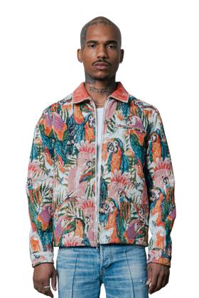 A man wearing a COÛT DE LA LIBERTÉ tropical parrot tapestry zip jacket with light-wash jeans