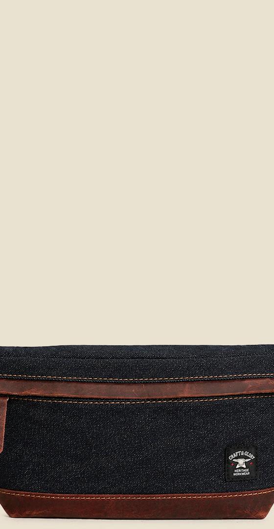 A Craft &amp; Glory denim and leather sling waist bag on a plain cream background
