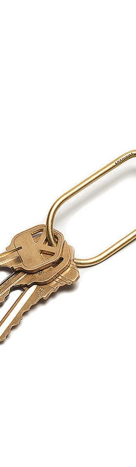 A brass Craighill wilson keyring with blue accent holding three keys on a white background