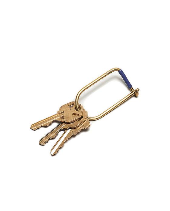 A brass Craighill wilson keyring with blue accent holding three keys on a white background