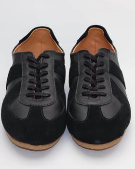 A pair of black leather and suede handmade sneakers on a plain white background