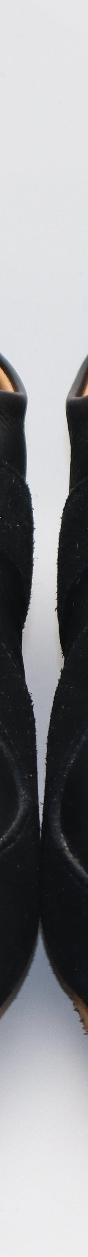 A pair of black leather and suede handmade sneakers on a plain white background