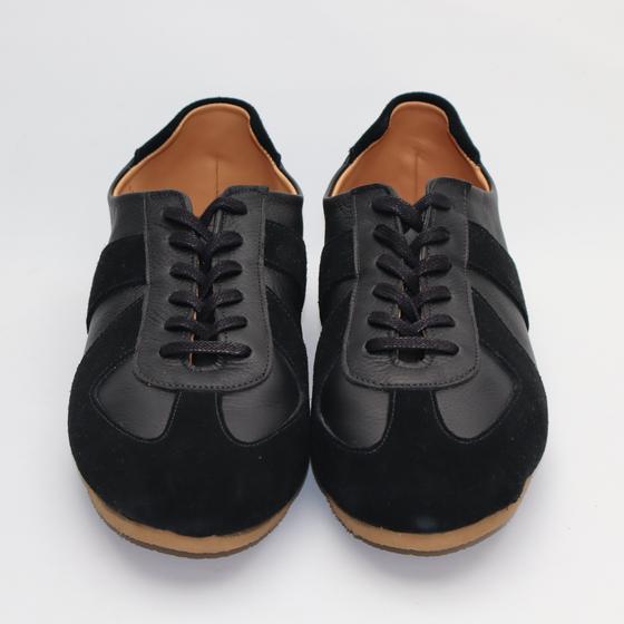 A pair of black leather and suede handmade sneakers on a plain white background
