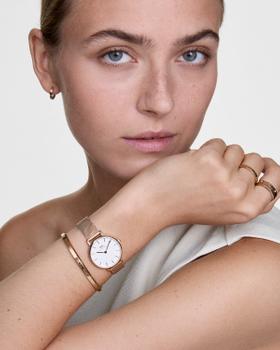 A woman wearing a rose gold Daniel Wellington mesh watch and bangle