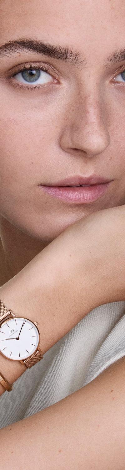 A woman wearing a rose gold Daniel Wellington mesh watch and bangle