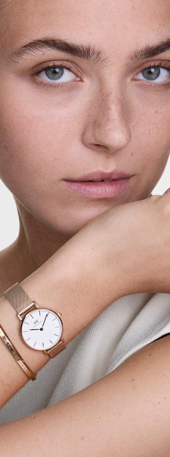 A woman wearing a rose gold Daniel Wellington mesh watch and bangle