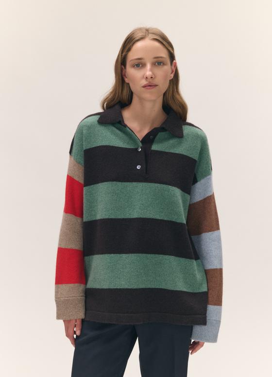 A woman wearing an oversized &Daughter striped wool rugby-collar sweater with contrast colour-blocked sleeves and navy trousers