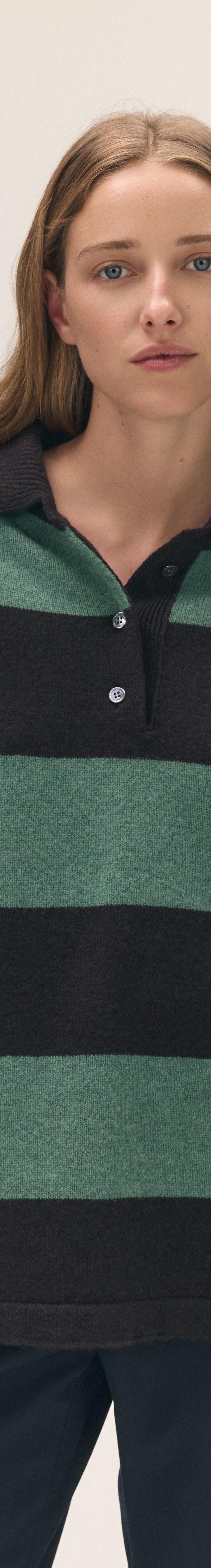 A woman wearing an oversized &Daughter striped wool rugby-collar sweater with contrast colour-blocked sleeves and navy trousers