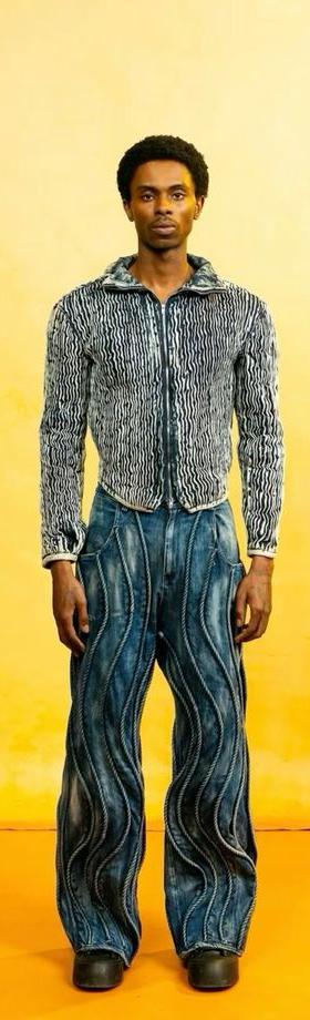 A man wearing a Daveed Baptiste textured denim jacket and swirl-panelled wide-leg jeans